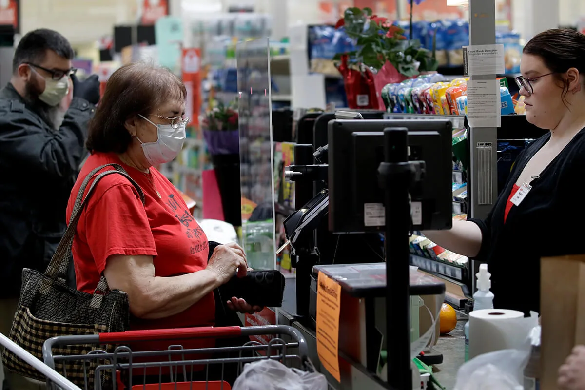 A woman checks out at the grocery store while wearing a mask.