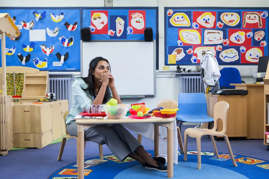 woman sitting alone at desk in preschool classroom