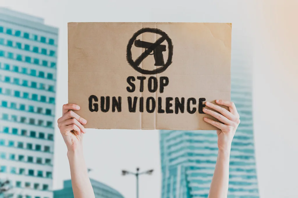 person holding sign that says "stop gun violence"