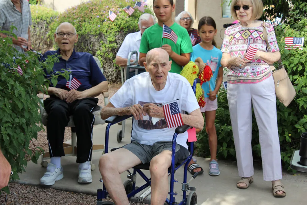 Chuck Shuff sitting outside in wheelchair holding American flag