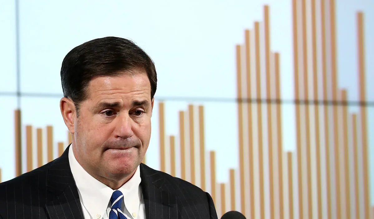 Gov. Ducey in front of a bar graph