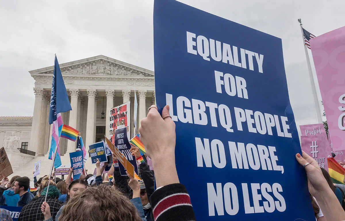person holding sign calling for LGBTQ rights in crowd outside of Supreme Court