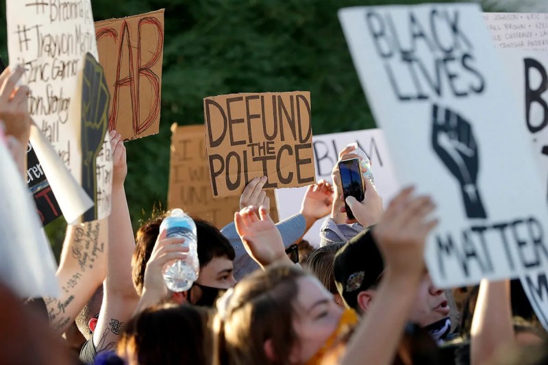 protesters holding signs, one saying "Defund Police"
