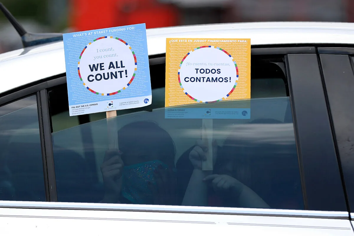 children holding signs in car saying "we all count"