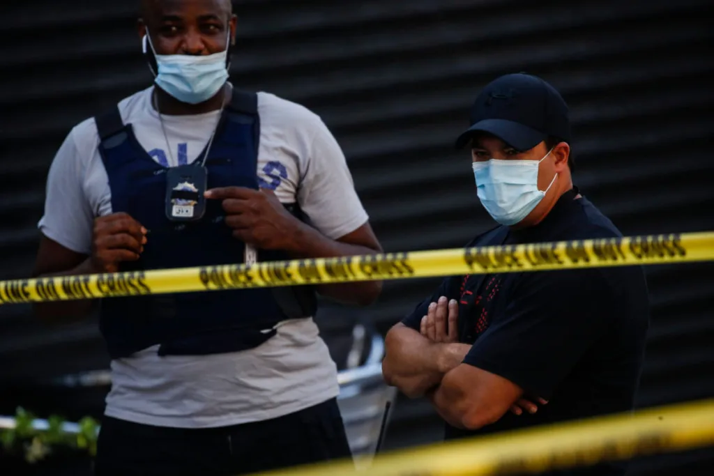 Police officers respond to a crime scene where a 23-year-old man was discovered with gunshot wounds to his legs and torso before being transported to a hospital where he died from his injuries in Brooklyn, New York. (AP Photo/John Minchillo)