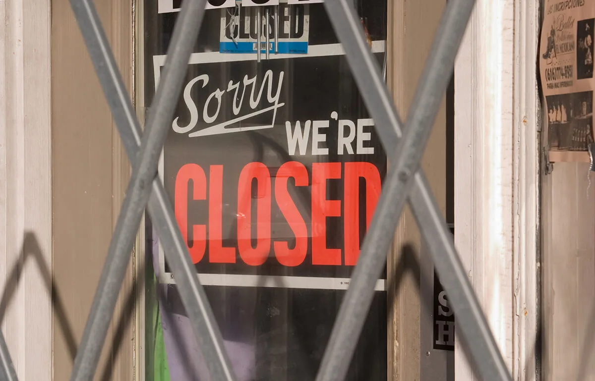 "sorry, we're closed" sign hanging on business