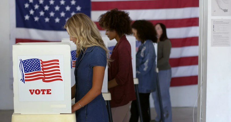 four women standing at polling booths