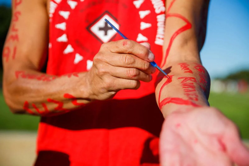 person painting words on their arm with red paint