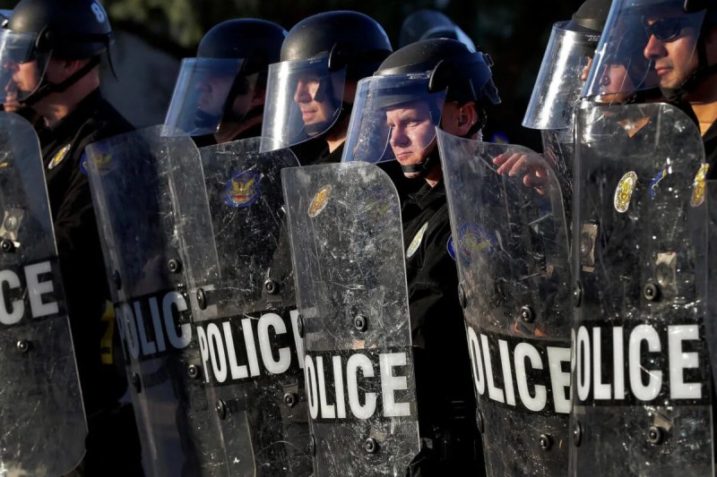 line of Phoenix police officers wearing riot gear and holding shields