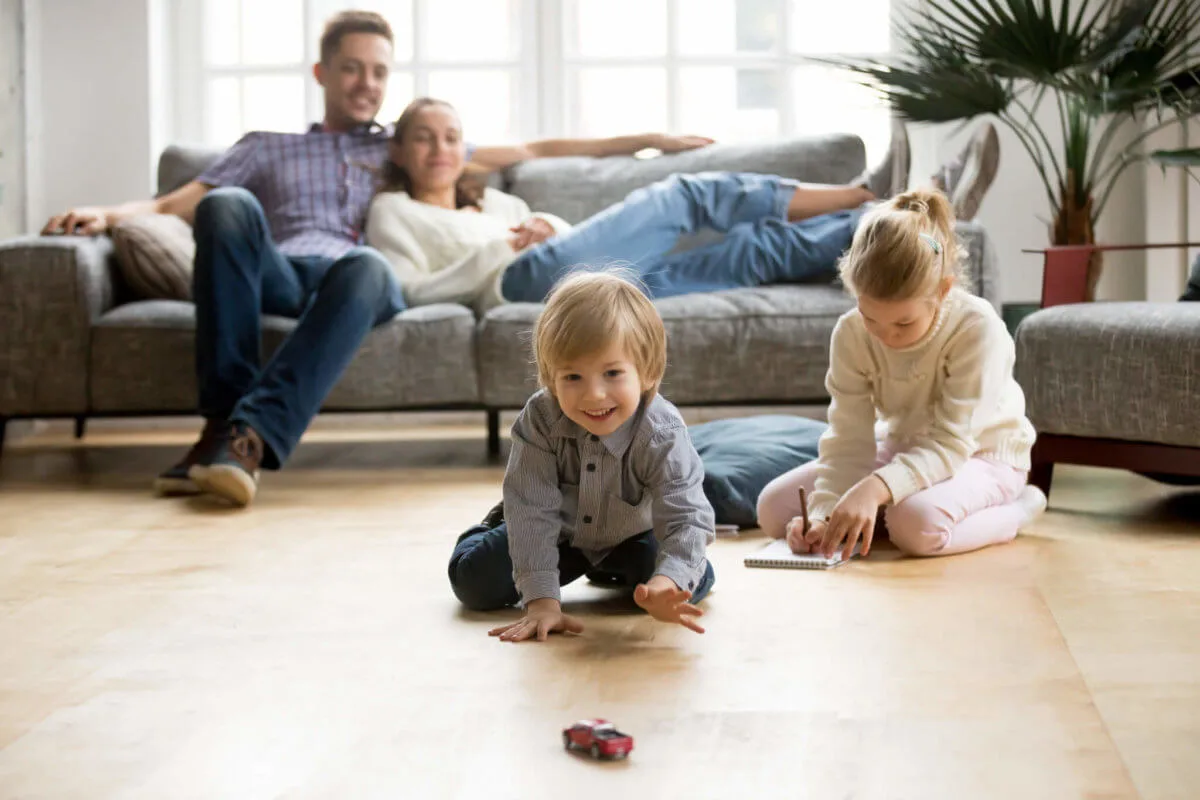 Cute kids playing while parents relaxing sofa at home together