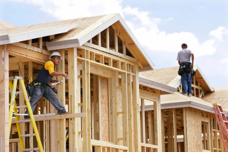 two construction workers working on roof frames