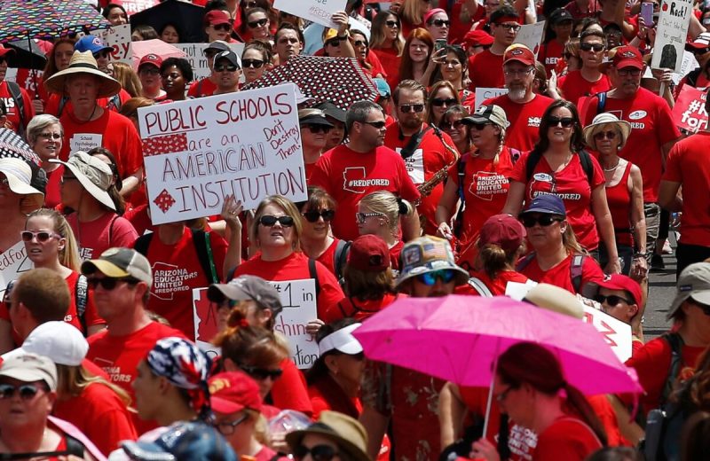 crowd of people wearing redshirts and holding protest signs