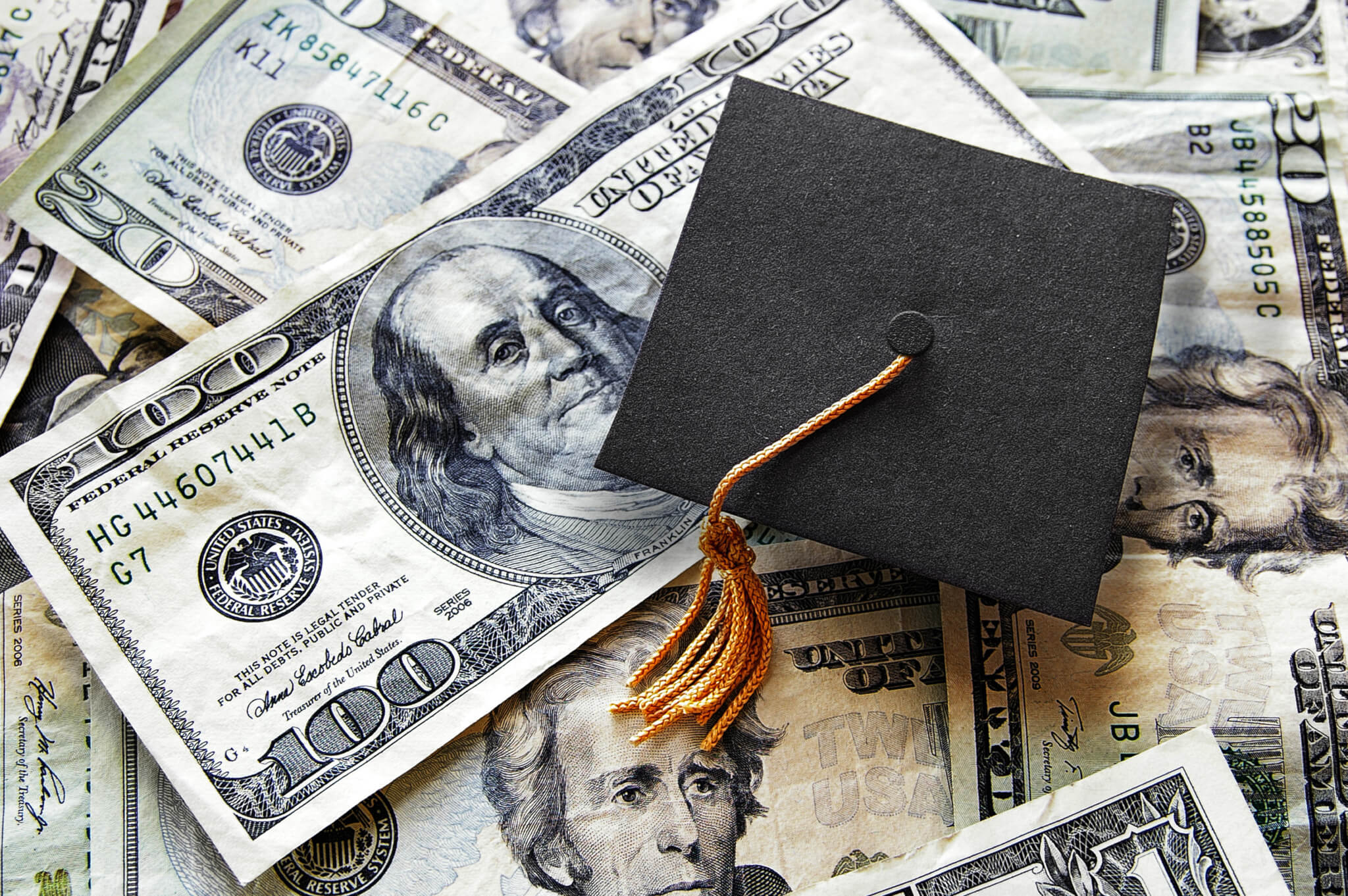 graduation cap over hundred dollar bills