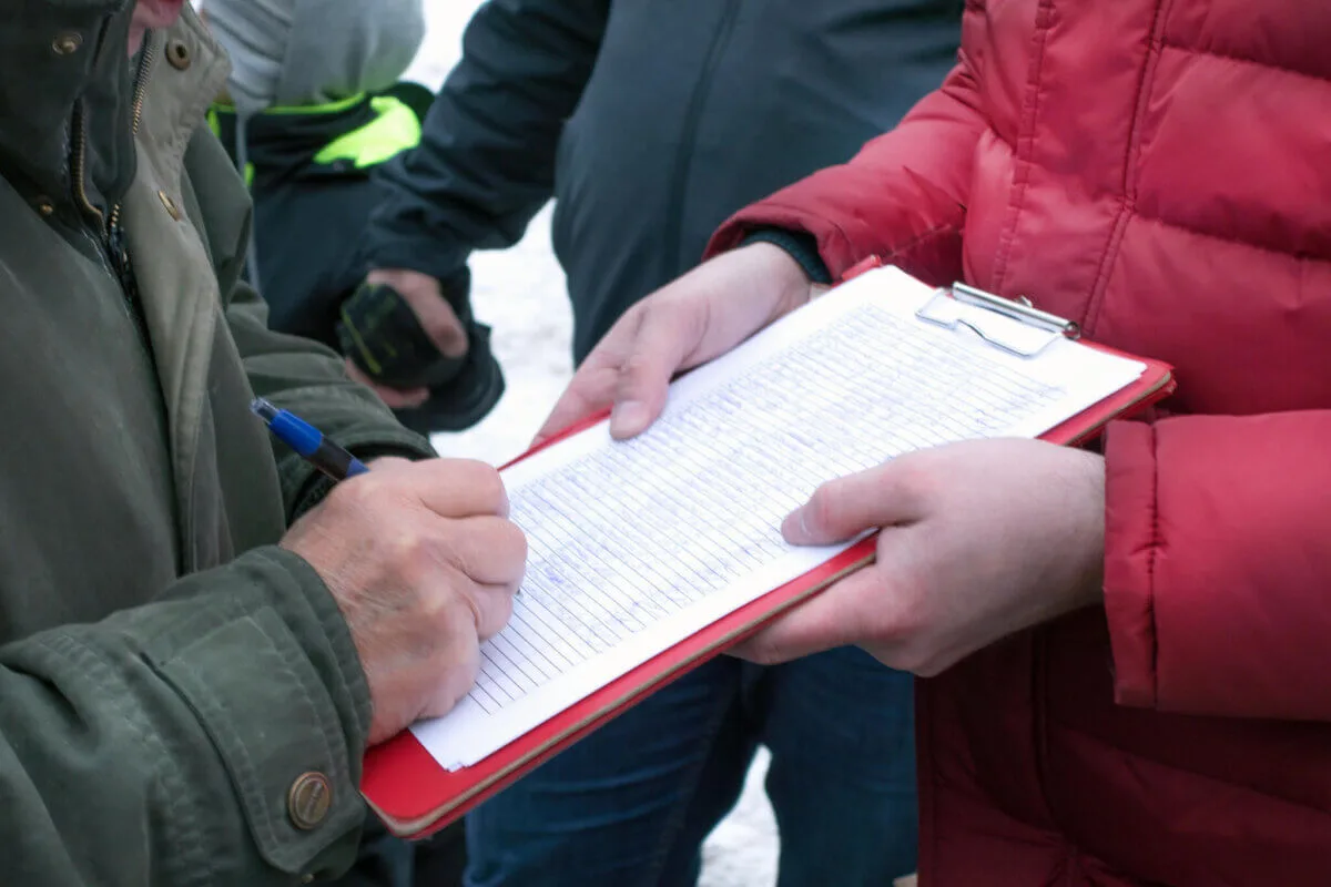 close up of someone one signing a petition on clipboard