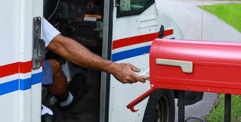 post office worker taking mail out of mailbox