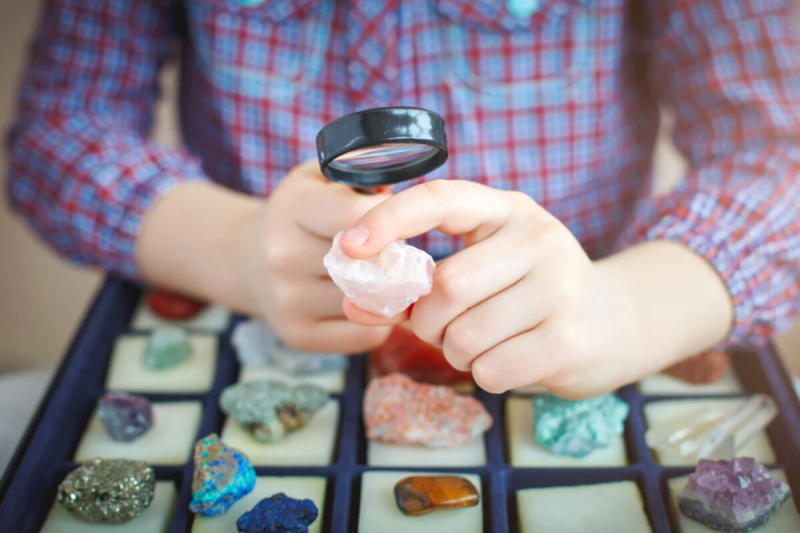 person looking at a rock with a magnifying glass