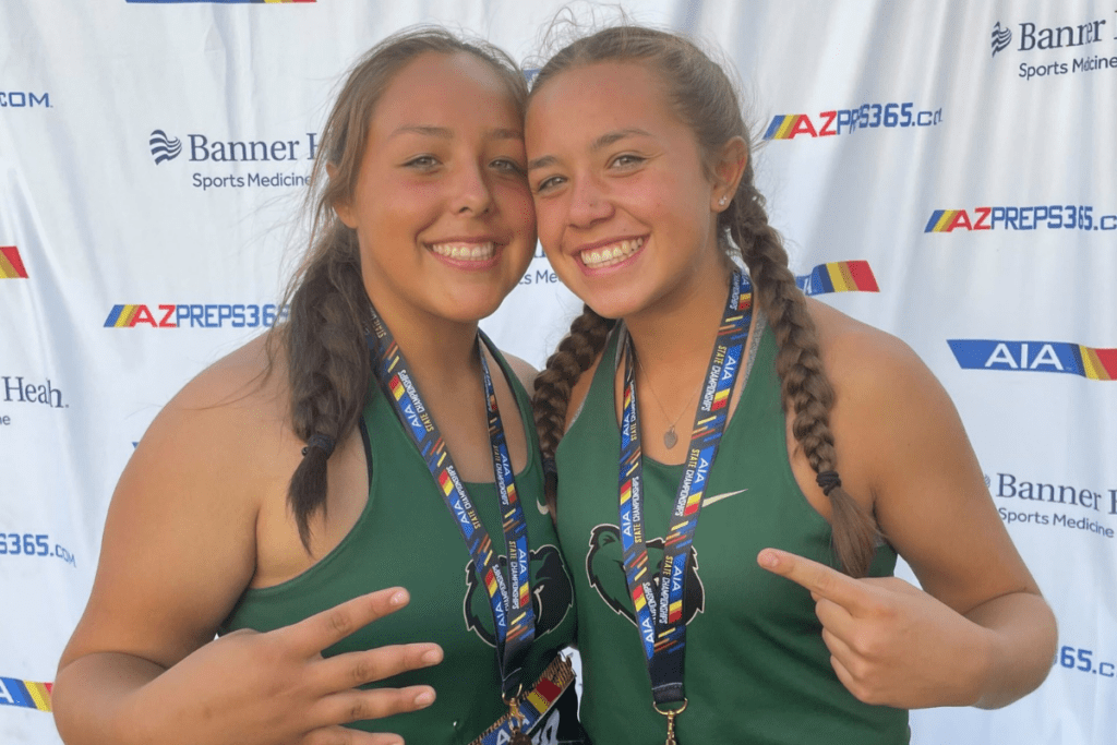 Sisters J.J. and Gabriella Garcia wearing track and field jerseys and medals