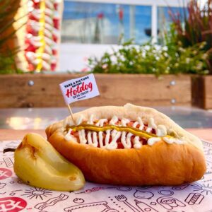 A Sonoran hot dog with a jalapeno on the side.