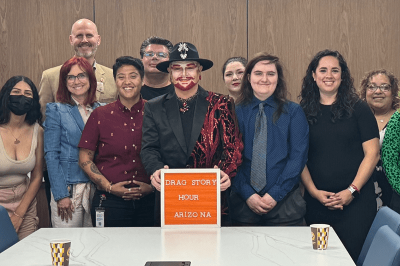 group of people standing behind Drag Story Hour Arizona sign