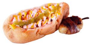 A Sonoran hot dog with a white cream sauce and green sauce with a bacon wrapped jalapeno on the side.