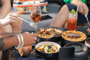 A restaurant table filled with shared plates and cocktails.