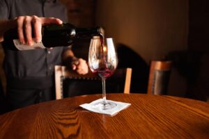A man filling a glass of red wine.