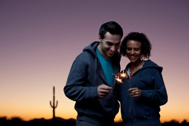 Couple playing with sparklers in desert.