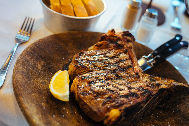 Close-Up Florentine T-Bone Steak and Lemon Wedge at a Steakhouse