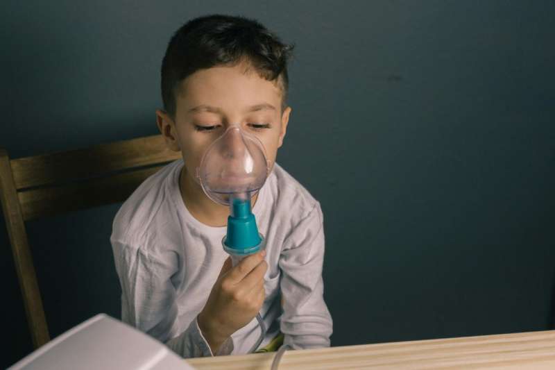 Child holding breathing mask to face.