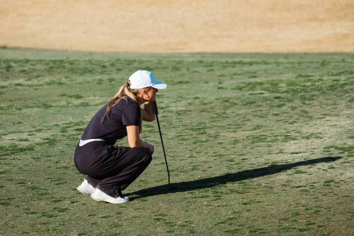 Female golfer crouching on the course.