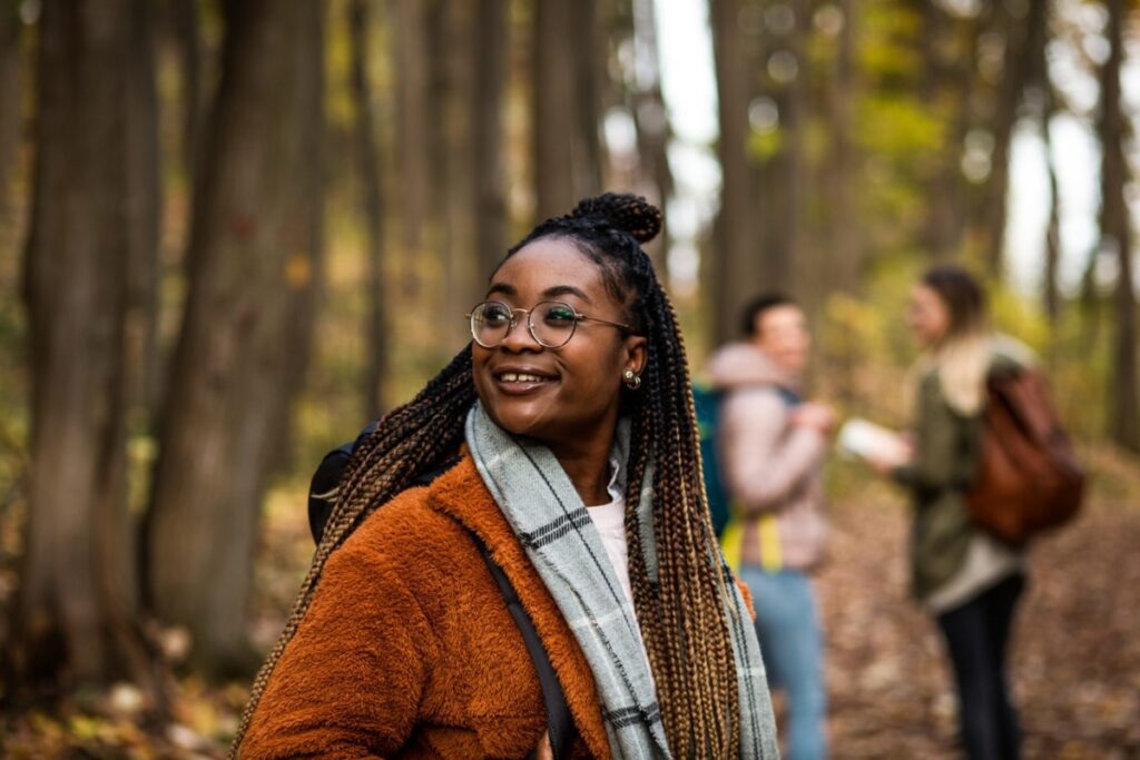 Three female friends having fun and enjoying hiking in forest.