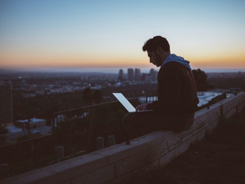 Young man working on a laptop while overlooking the city.