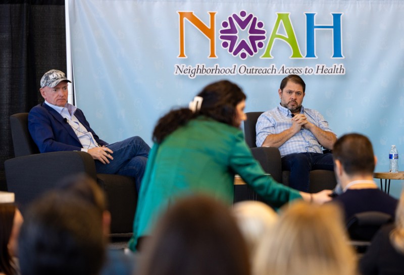Mark Kelly and Ruben Gallego on stage listening to someone in crowd speak