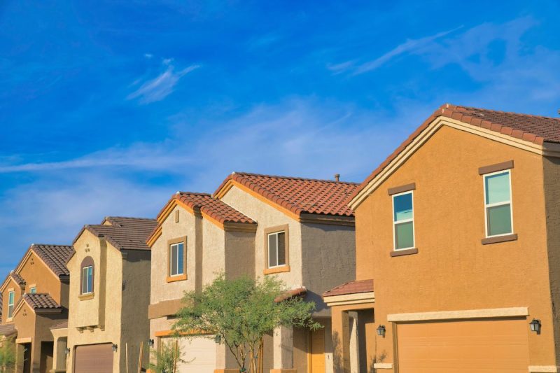 Row of houses with painted stucco walls and clay tile roofs against the blue sky at the back.