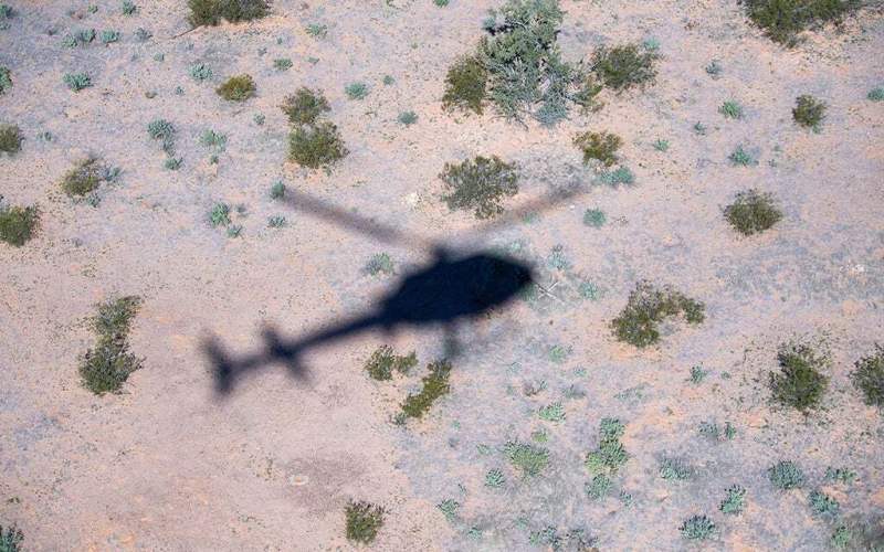 A Customs and Border Protection helicopter casts a shadow in the desert on the Tohono O’odham Nation