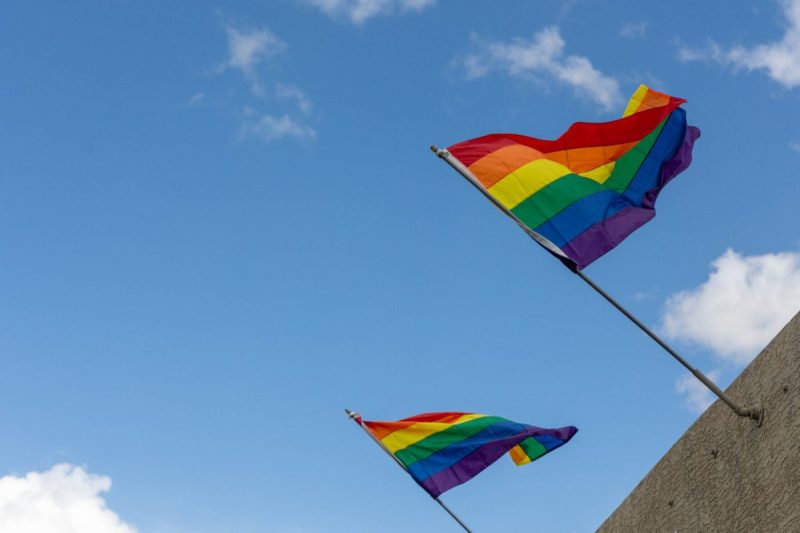 pride flags waving under a blue sky