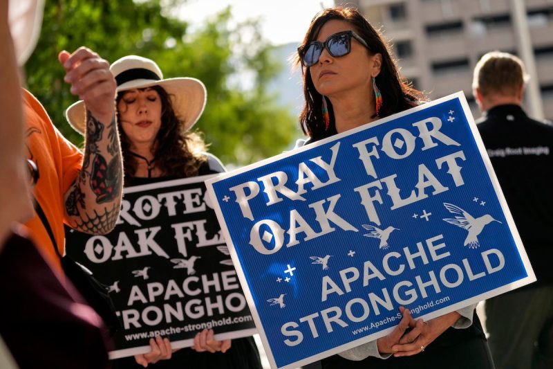 two women holding signs that say pray for Oak Flat
