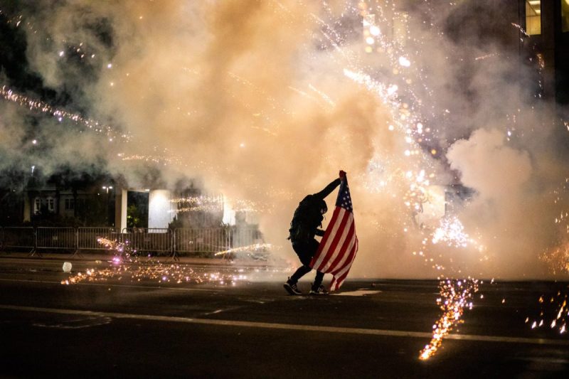 protester uses an American flag to shield himself from tear gas used by Phoenix police