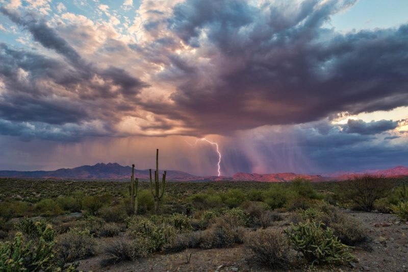 a vibrantly colored sky and a thunder bolt appear over the desert