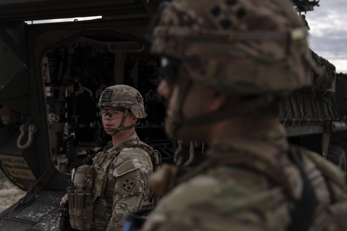 A man is halted climbing the US-Mexico border wall. Under new Trump rules, US troops sound the alarm