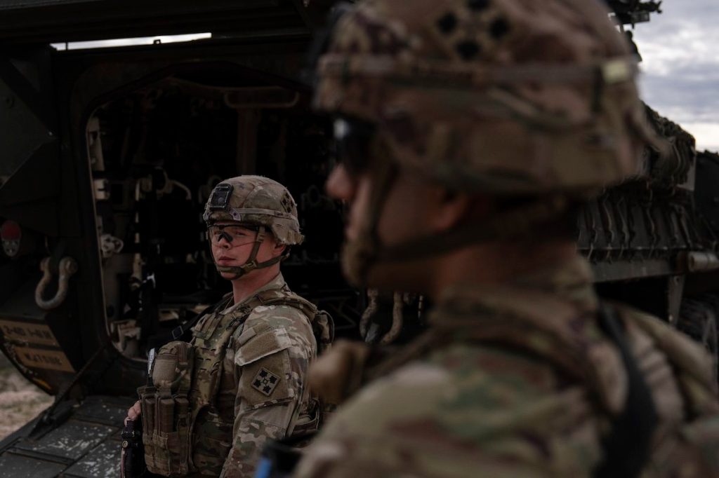 A man is halted climbing the US-Mexico border wall. Under new Trump rules, US troops sound the alarm