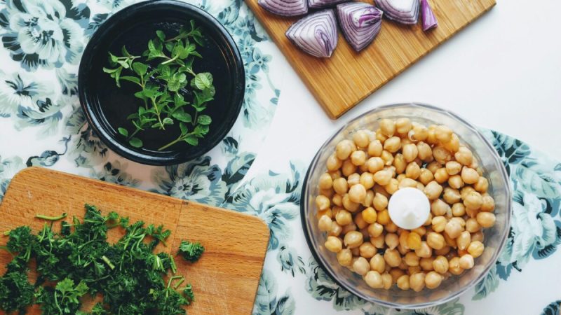 a bowl of chickpeas alongside fresh herbs and shallots