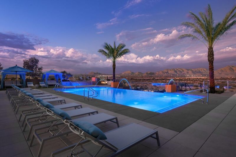 a blue rooftop pool in arizona surrounded by the sky and palm trees