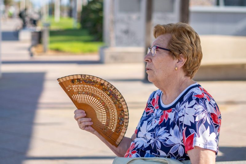 old woman fanning herself outdoors
