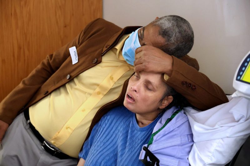 Junior Clase leans on his wife, Solibel Olaverria, at a rehabilitation facility