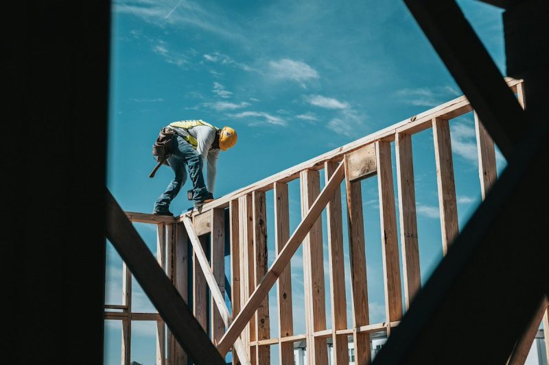 construction worker standing on beam working on a house
