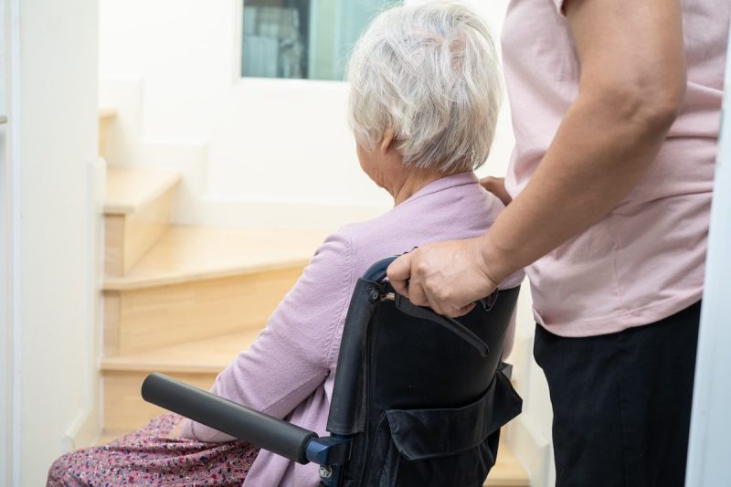 woman pushing an old woman in a wheelchair into a room