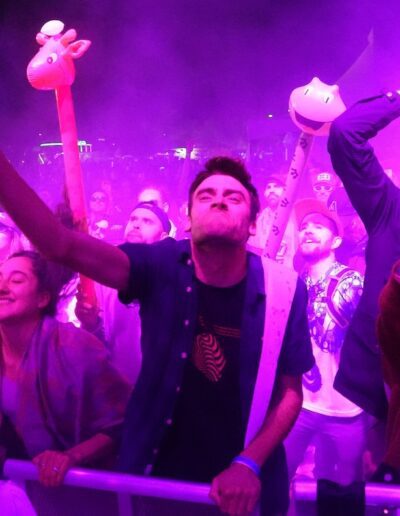 people dancing at the barrier at a concert with a purple light over them