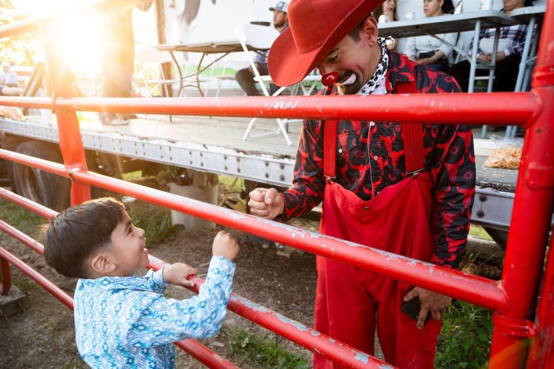 Rodeo clown gives a fist bump to a child