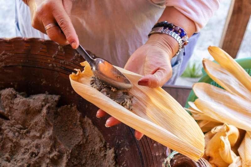 hands putting beans into a tamale